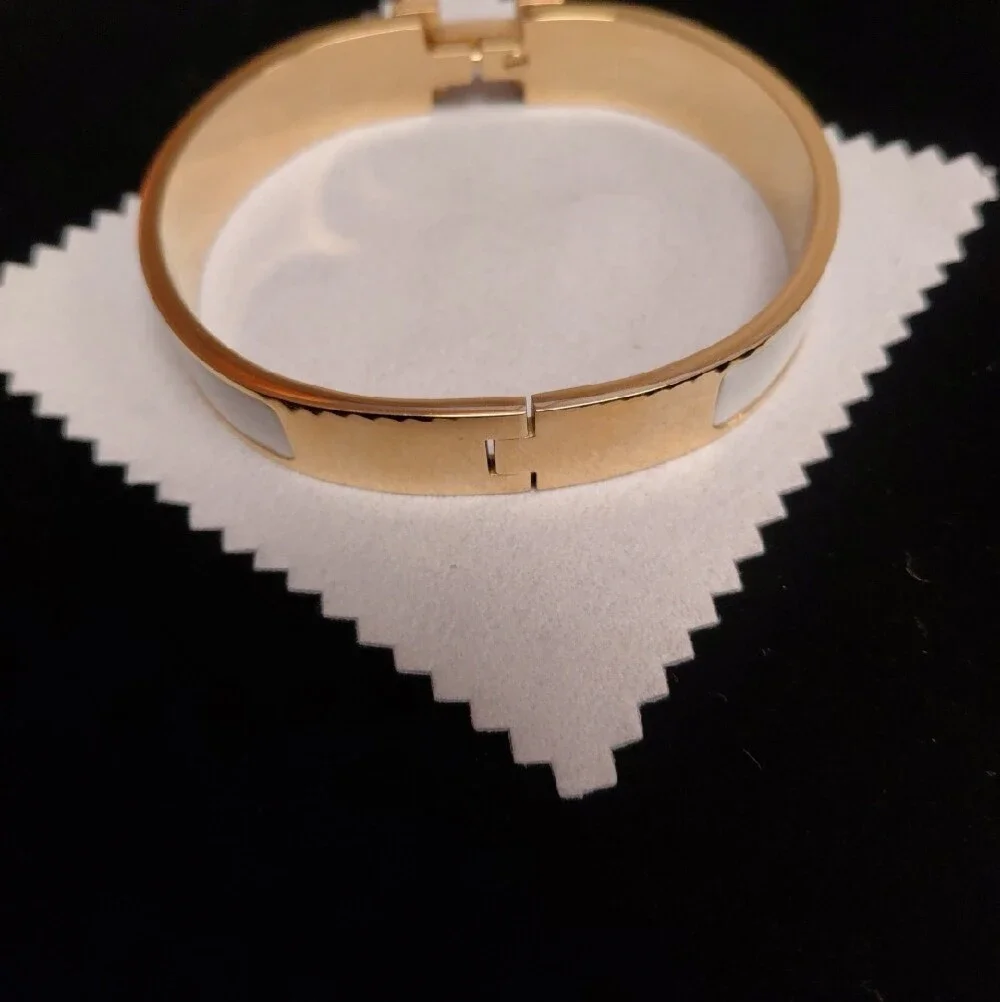 HERMES Gold and White Enamel Click H Bracelet with Signature H Accent.